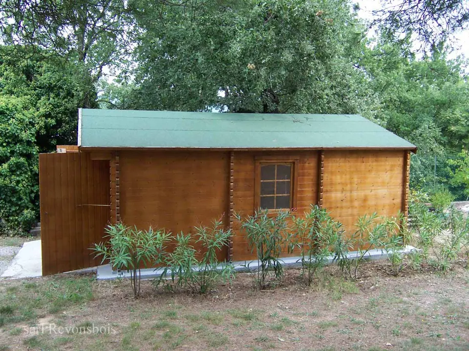 Garage en madriers lasuré, toit vert, jardin