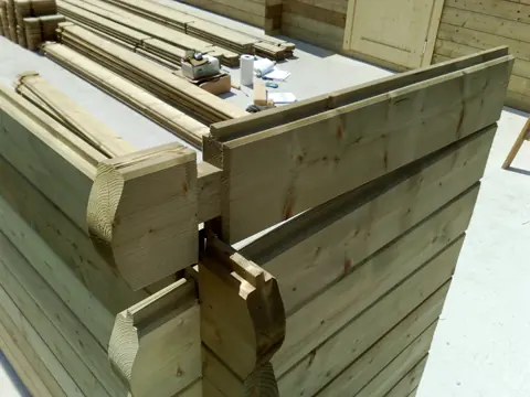 Angle de madriers emboîtés en haut de mur
