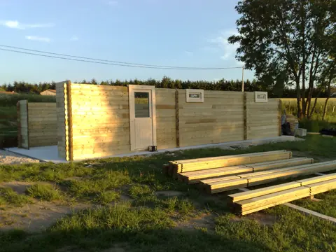 Murs en madriers montés, bois en attente au sol