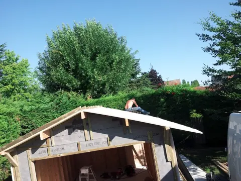 Garage ossature, charpente posée, jardin arboré