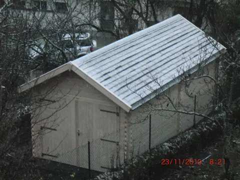 Garage en madriers, toit enneigé, vue haute