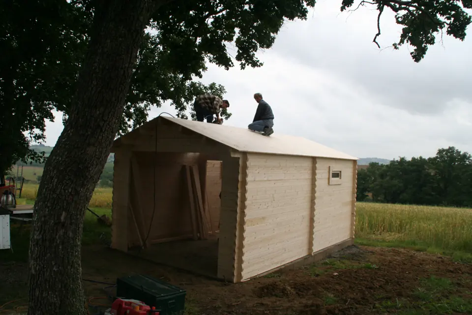 Garage en madriers sous les arbres en montage