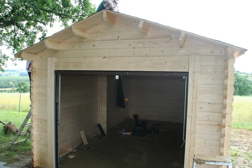 Garage en madriers, ouverture de porte, toit voligé