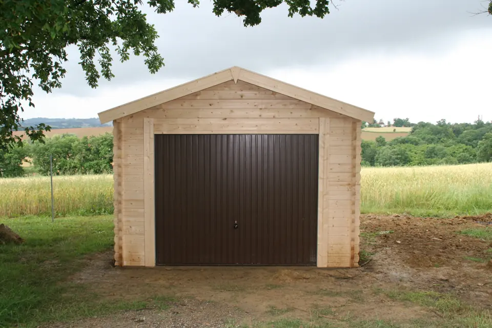 Garage en madriers, porte basculante brune, campagne