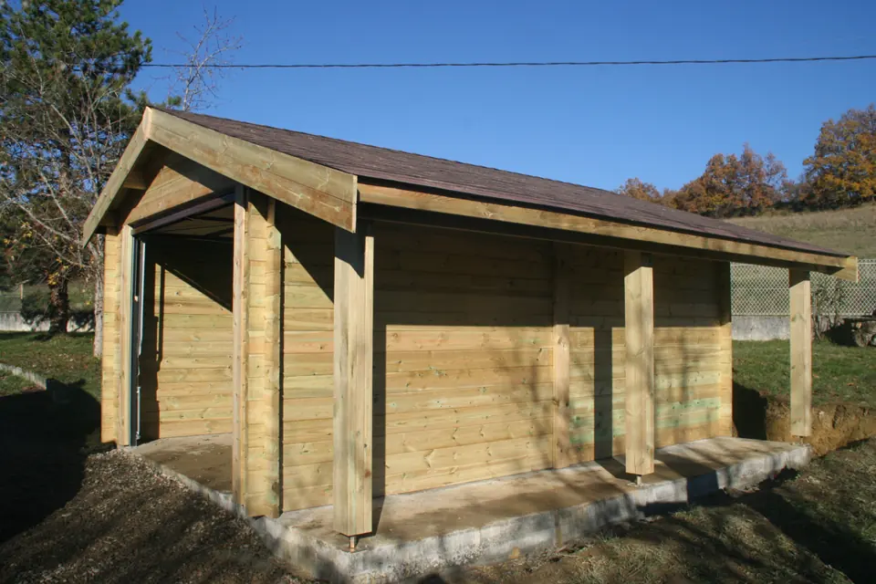 Garage en madriers avec abri ouvert latéral, ciel bleu