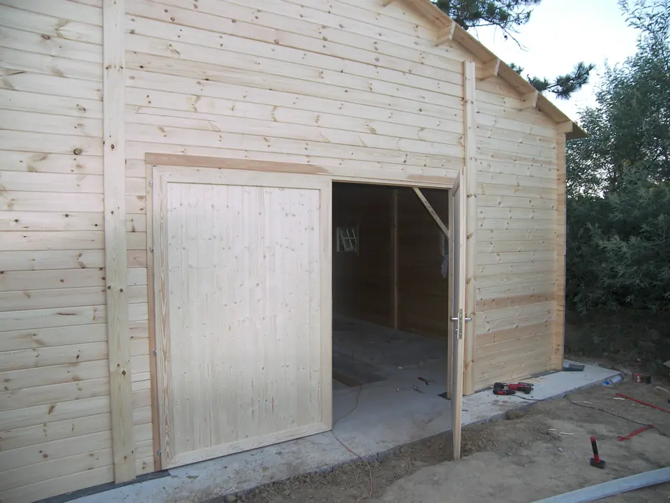 Garage en madriers bruts, porte double entrouverte