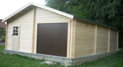 Long garage en madriers, porte brune