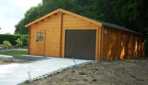Garage en madriers lasuré, porte brune, allée