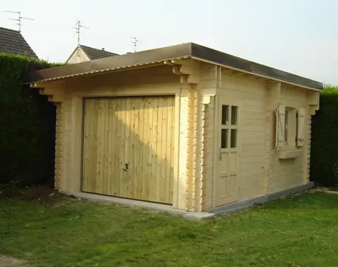 Garage en madriers, porte bois, haie fleurie
