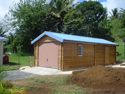 Garage en madriers, toit bleu, terrain en travaux