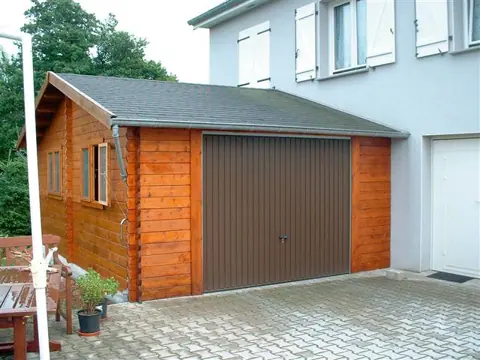 Garage en madriers lasuré orangé, porte brune