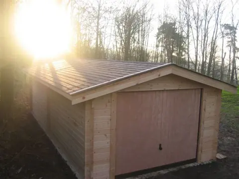 Garage en madriers en contre-jour, sous-bois