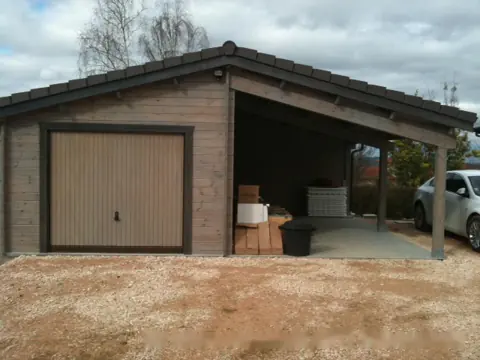 Garage en madriers avec carport, porte brune