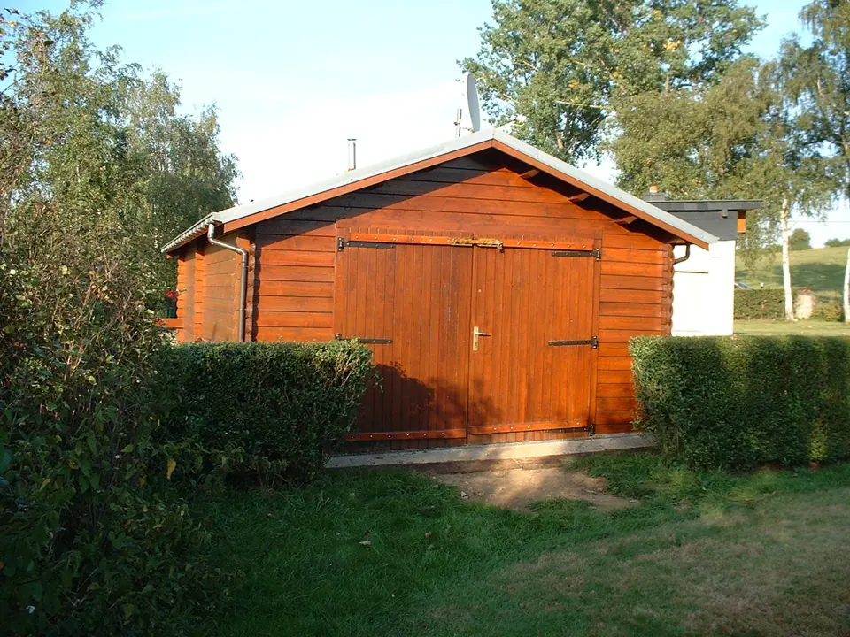 Garage double en madriers lasuré rouge, haie