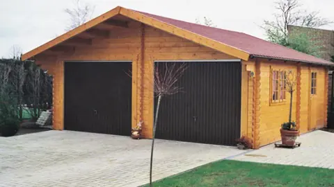 Garage double en madriers, portes brunes, tuiles