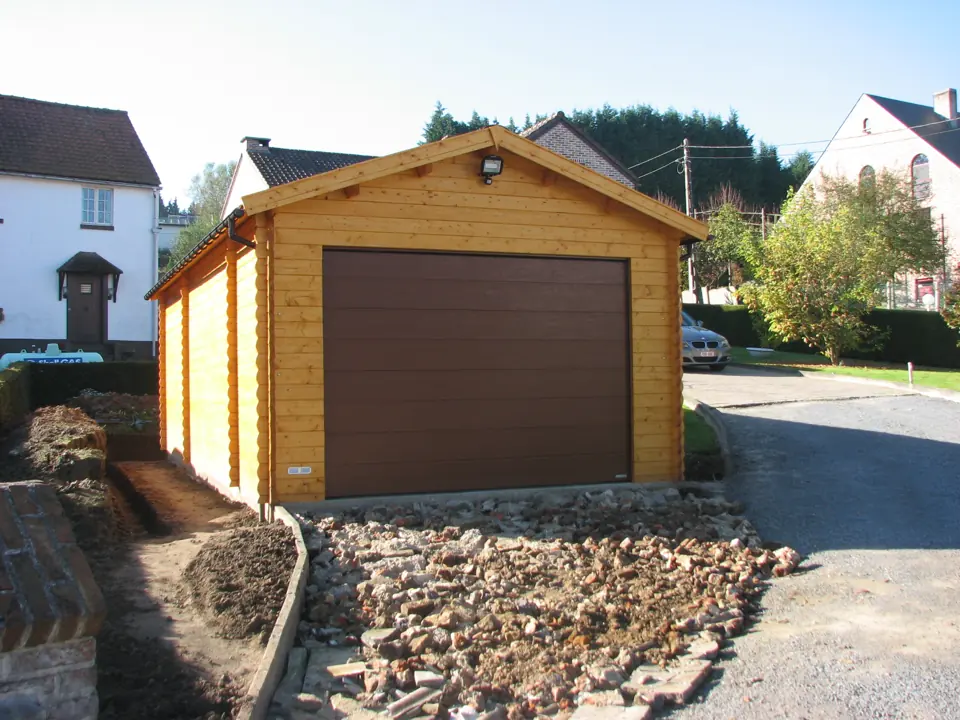 Garage en madriers, porte brune, terrain en travaux