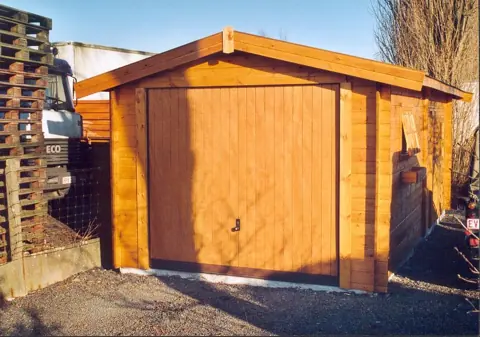 Garage en madriers lasuré, porte basculante bois