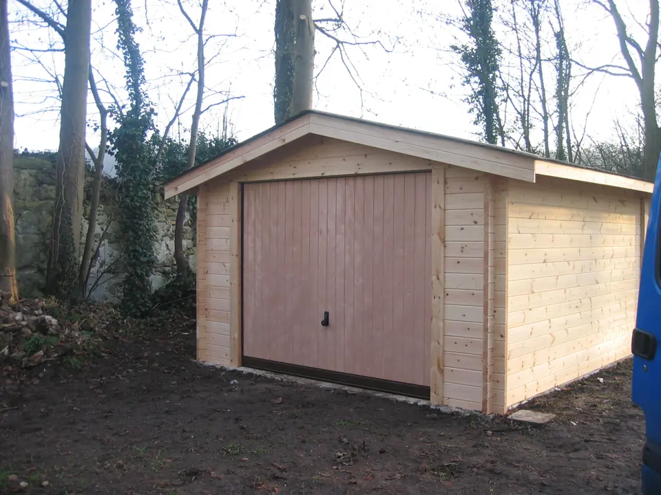 Garage en madriers, porte basculante claire, sous-bois