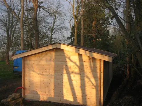 Garage monopente en madriers dans un sous-bois