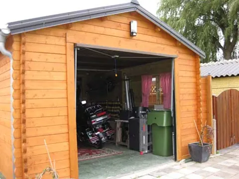 Garage en madriers lasuré ouvert, intérieur encombré