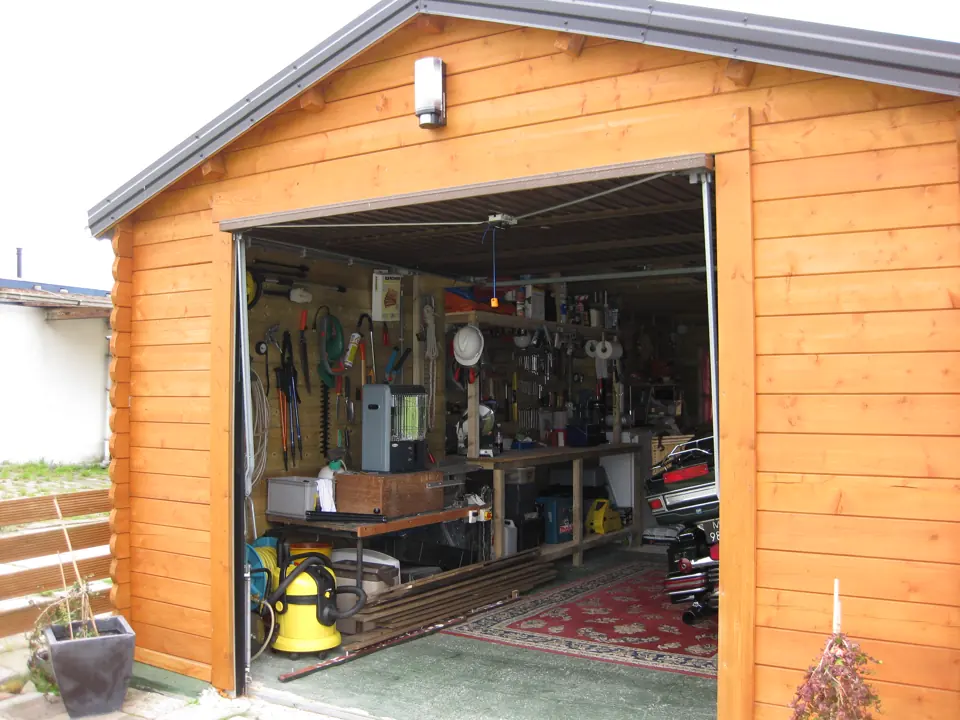 Garage en madriers ouvert sur un atelier rangé