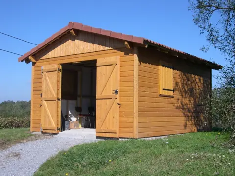 Garage ossature lasuré, porte ouverte, ciel bleu